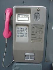 Magenta-farbener Telefonhörer an einem Münzfernsprecher der Deutschen Telekom