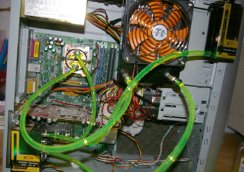Probeaufbau einer Wasserkühlung (Thermaltake) in einem AMD-Rechner. Links unten Pumpe; darüber CPU-Kupferkühler, oben großer Kühler mit Lüfter, 120 mm Durchmesser, rechts davon Ausgleichsbehälter